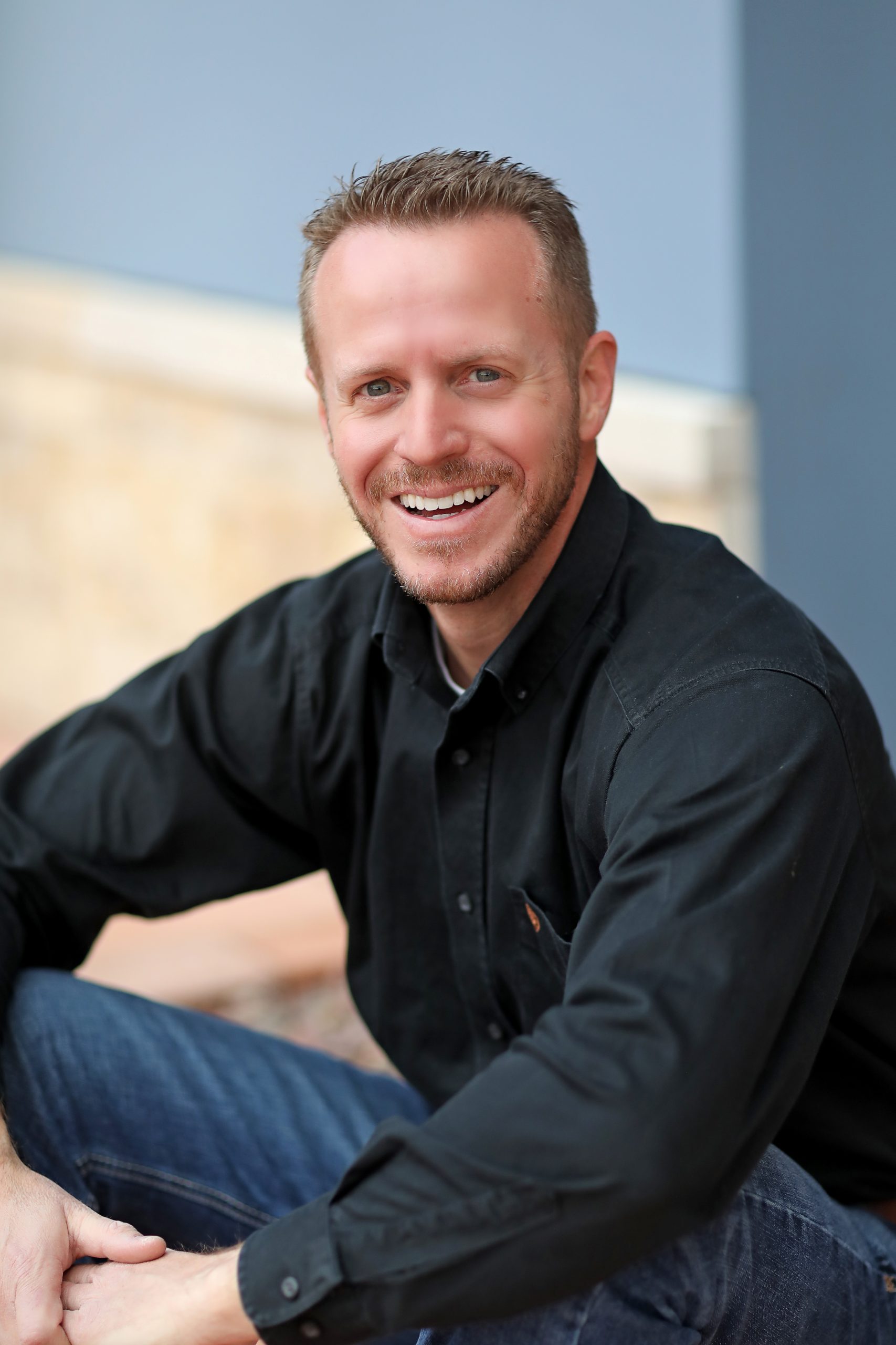 Sun City West cosmetic dentist, Dr. Mathew Harmon, sitting and smiling for a professional photo